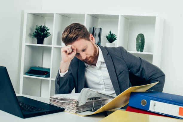 istock Businessman holding fist on his head reading paperwork 945070490