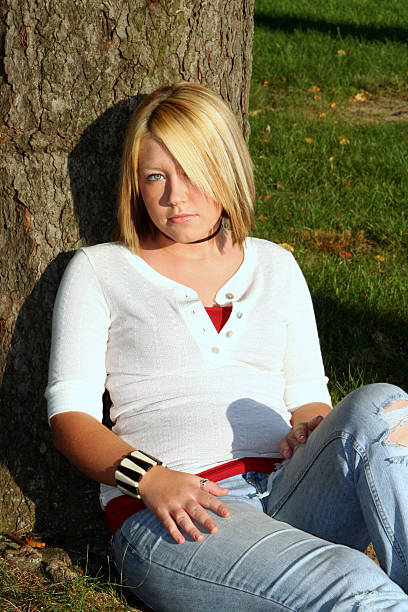 Femme blonde assise sur le sol par arbre - Photo