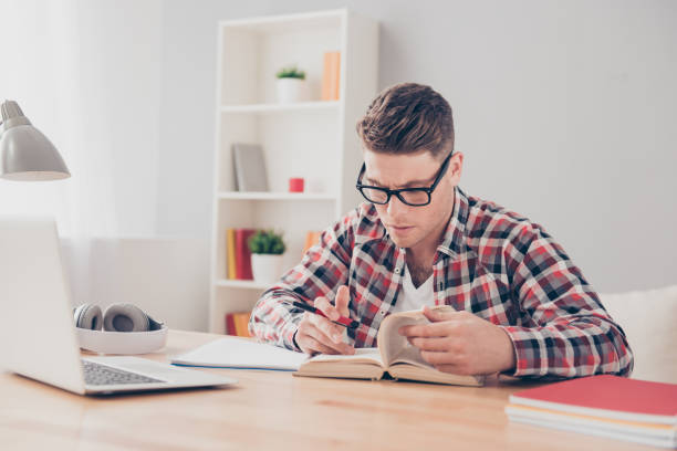 istock Young concentrated student reading book and preparing for lessons 945075058