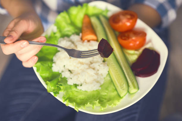 istock A girl holds a plate with rice and vegetables 945078006