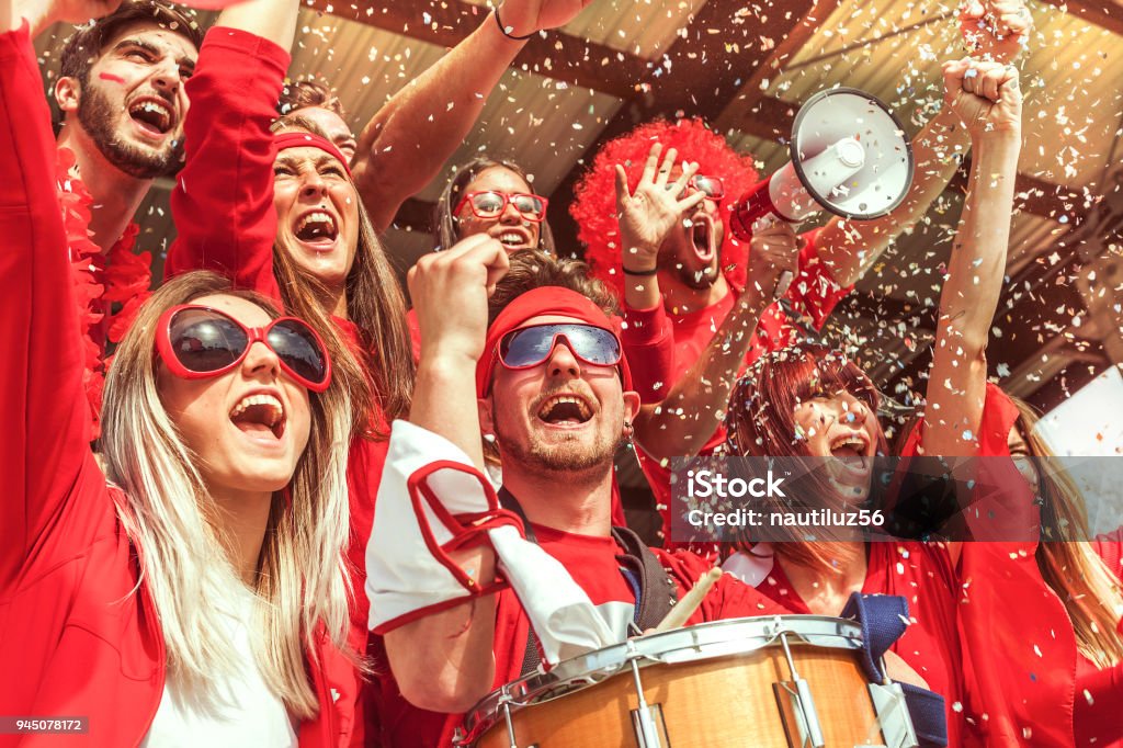 gruppo di fan vestiti di colore rosso guardando un evento sportivo - Foto stock royalty-free di Fan