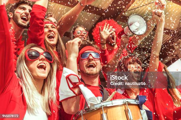Gruppo Di Fan Vestiti Di Colore Rosso Guardando Un Evento Sportivo - Fotografie stock e altre immagini di Fan