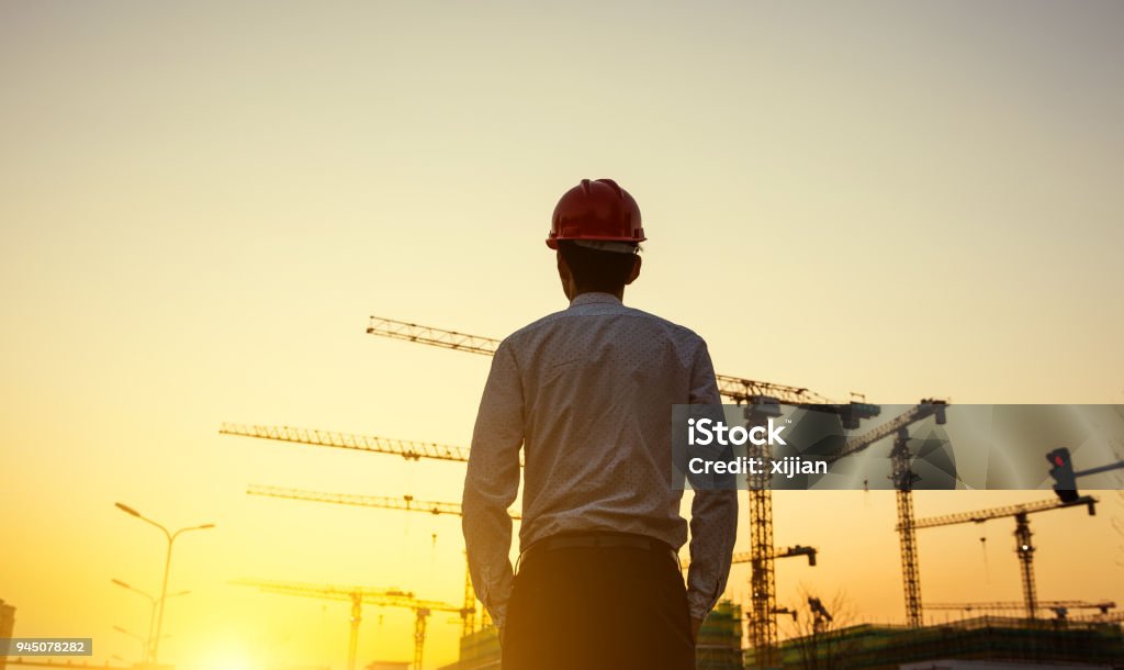 Ingenieur mit Kran Hintergrund bei Sonnenuntergang - Lizenzfrei Baustelle Stock-Foto