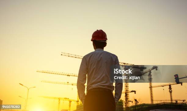 Ingenieur Mit Kran Hintergrund Bei Sonnenuntergang Stockfoto und mehr Bilder von Baustelle - Baustelle, Baugewerbe, Ingenieur