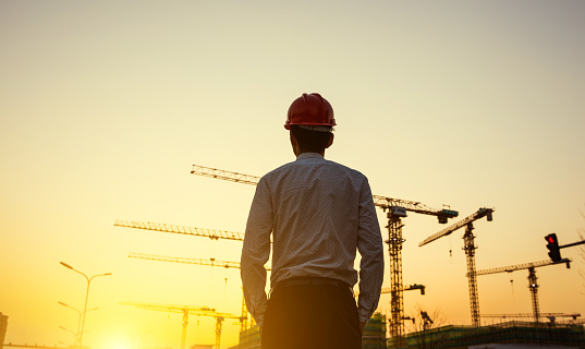 Engineer with crane background at sunset