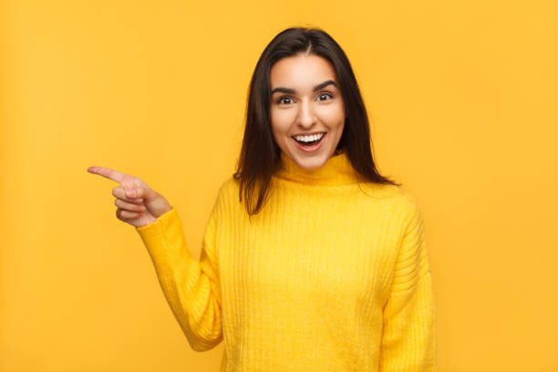 istock Amazed brunette pointing away on yellow 945078802