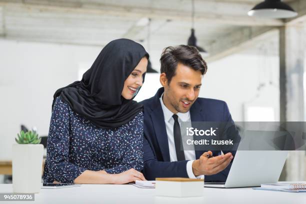 Muslim Businesswoman In Discussion With Colleague Stock Photo - Download Image Now - Office, West Asian Ethnicity, 20-29 Years