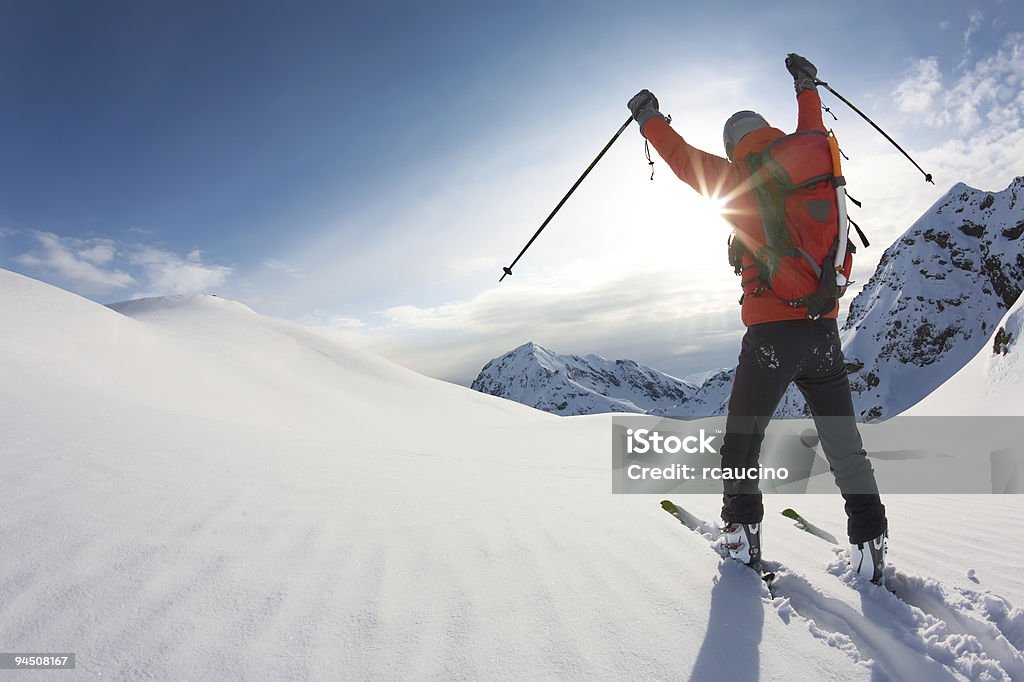 Skier reaches his arms up over a snowy mountain landscape  Mountain Stock Photo