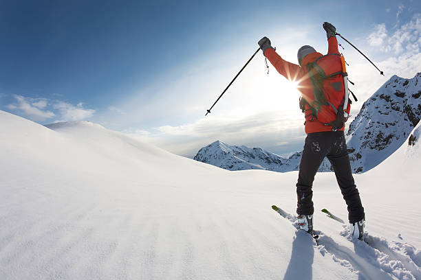 Skier reaches his arms up over a snowy mountain landscape stock photo