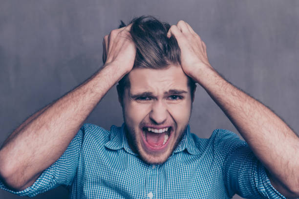 istock Young aggressive tired man touching head and yelling 945082182