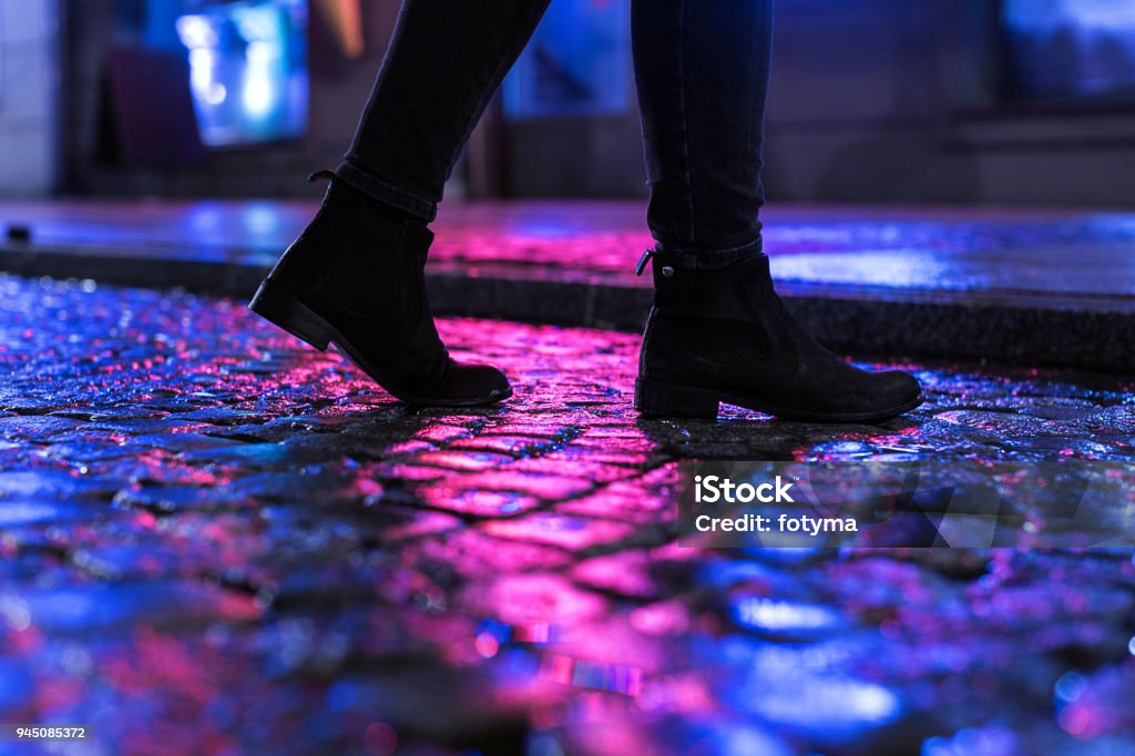 The night walk Woman in black shoes walking through the city street in the night Night Stock Photo