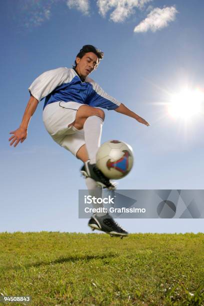 Foto de Jogador De Futebol Chutando A Bola Jumping e mais fotos de stock de Adulto - Adulto, Atleta, Azul