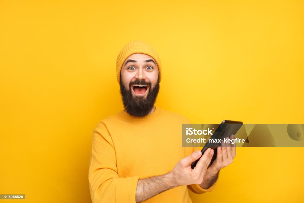 Mec excité en jaune avec tablette - Photo de Hommes libre de droits
