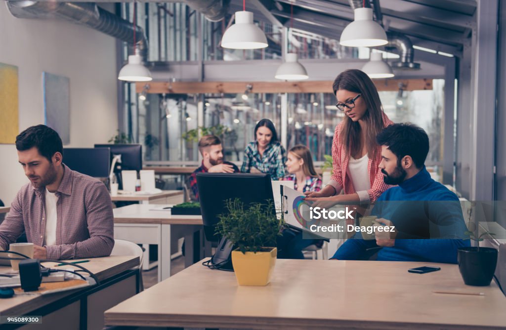 Young woman showing diagrama of growth to her colleague Coworking Stock Photo