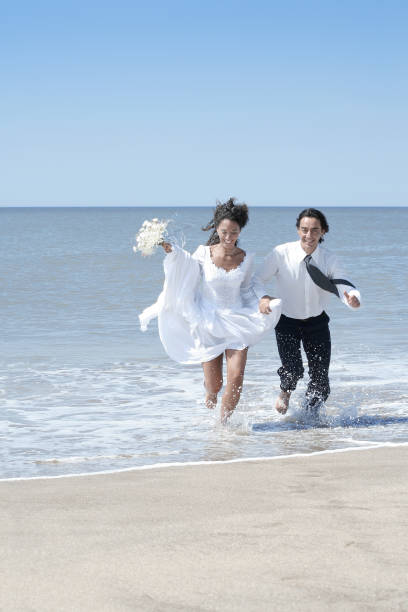 istock Bride and groom running at the beach 94509059