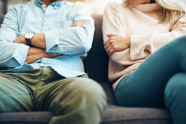 Every relationship has it's ups and downs Cropped shot of an unrecognizable mature couple sitting on the sofa with their arms folded after an argument separation stock pictures, royalty-free photos & images