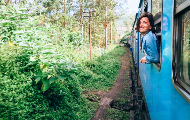 la donna felice guarda fuori dal finestrino del treno durante il viaggio sulla strada ferroviaria più pittoresca dello sri lanka - tea island foto e immagini stock