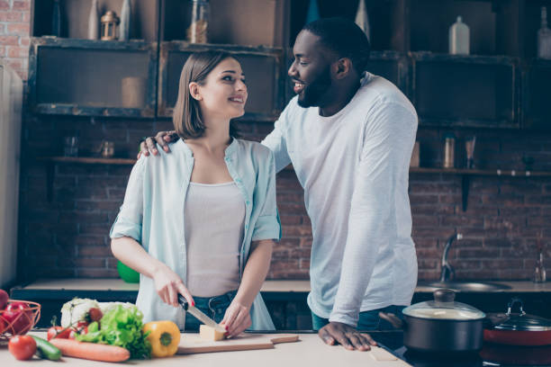 istock two lovely mixed race people together cooking healthy breakfast with cheese. Handsome afro american guy flirting with his  beautiful caucasian girl  in kitchen 945101042