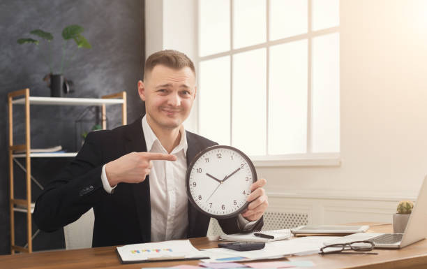 istock Businessman holding clock and pointing on it 945102098