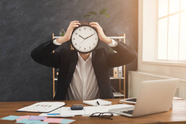 Businessman holding clock, covering face