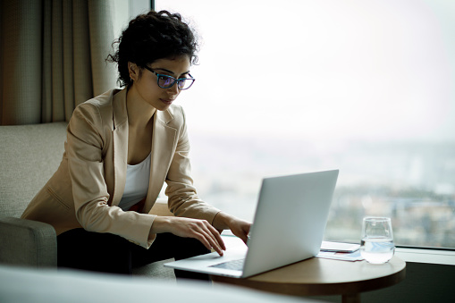 Young and beautiful businesswoman working on laptop in a hotel room