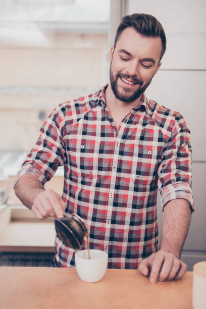 Portrait of handsome smiling barista pouring coffee in cup