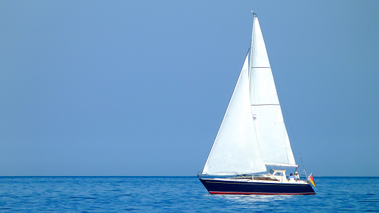 white sailboat or yacht on a lake or sea in sunny weather and blue water