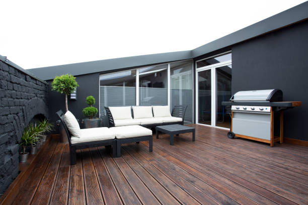 Grill on terrace with plants Grill and white garden furniture on wooden floor of terrace with plants and black brick wall apartment balcony garden stock pictures, royalty-free photos & images