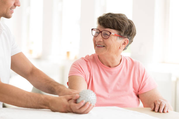 Older woman in hand physiotherapy A doctor helping an older woman with a hand ball exercise in physiotherapy at a bright office infarction photos stock pictures, royalty-free photos & images