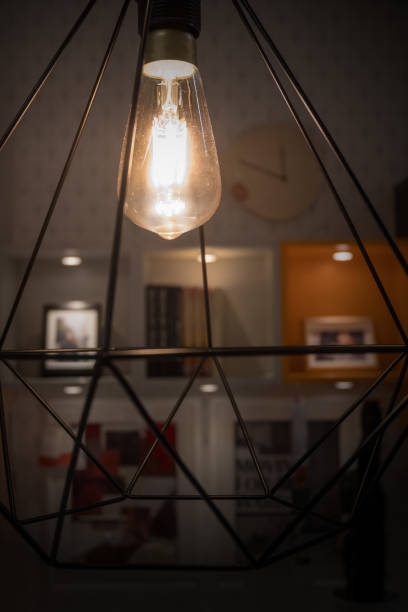 istock A glowing light bulb in modern lamp with blurred decoration shelf background 945116158