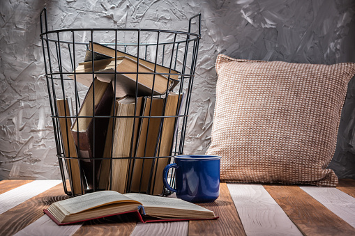 Old books in a metal basket on a wooden table. Old book open on a wooden table. Education, leisure concept.