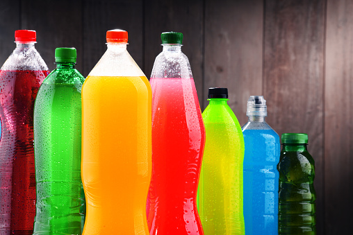 A vivid display of colorful beverage bottles in a row with striking contrast against a blue backdrop.