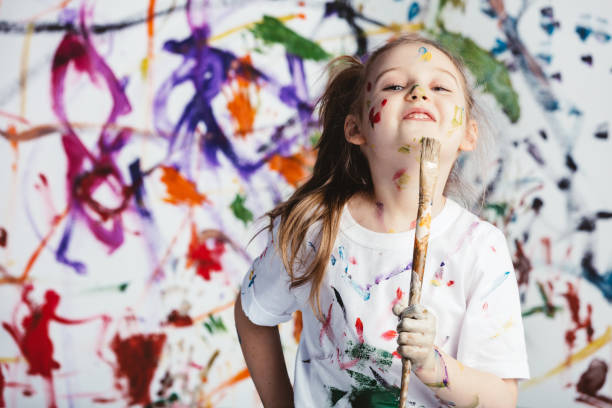 Young child painter standing with a brush Young child painter standing with a brush in front of a messy background. Creativity. child behaving badly stock pictures, royalty-free photos & images