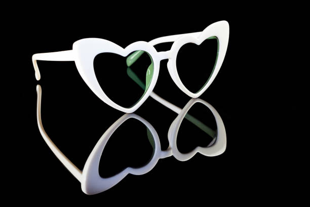 istock White heart shaped sunglasses on a black background. 945124200