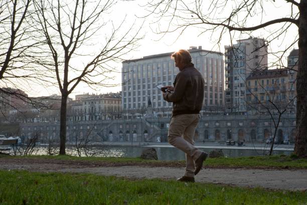 istock Casual businessman walks along river bank using tablet computer 945129512