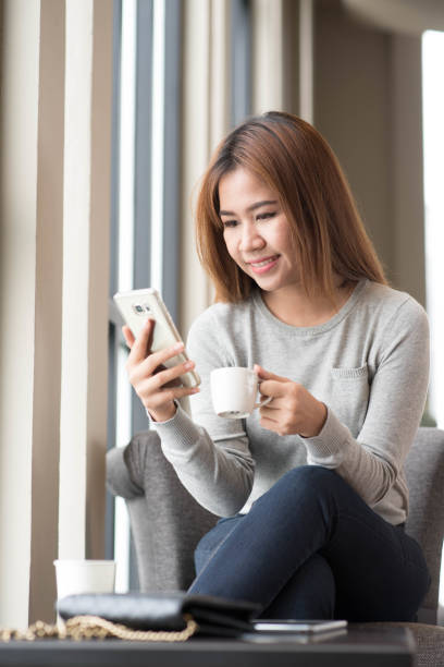 istock Woman using smartphone in coffee shop with image reflection on glass, internet of things conceptual 945140576