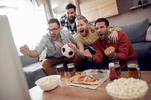 Soccer fans watching game in the living room,having fun together.