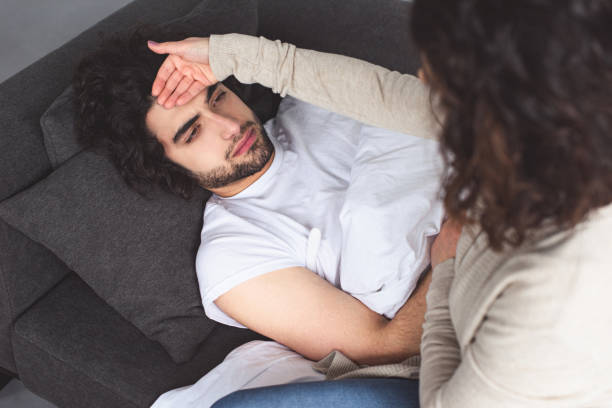 istock high angle view of girlfriend touching sick boyfriend forehead at home 945145132