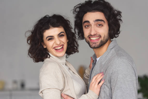 istock smiling young couple hugging and looking at camera at home 945147972
