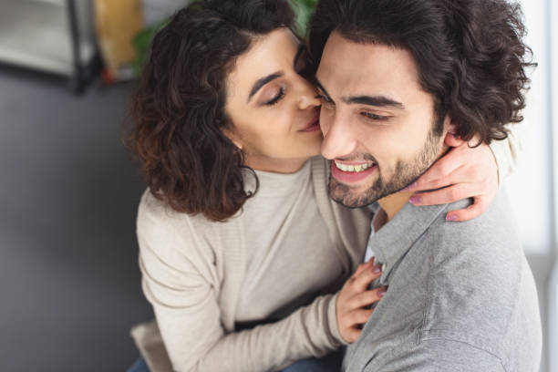 istock girlfriend kissing smiling boyfriend at home 945148706