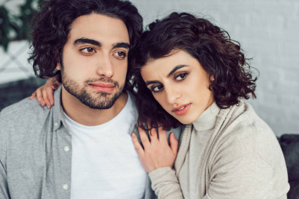 istock young couple hugging and looking away at home 945149098