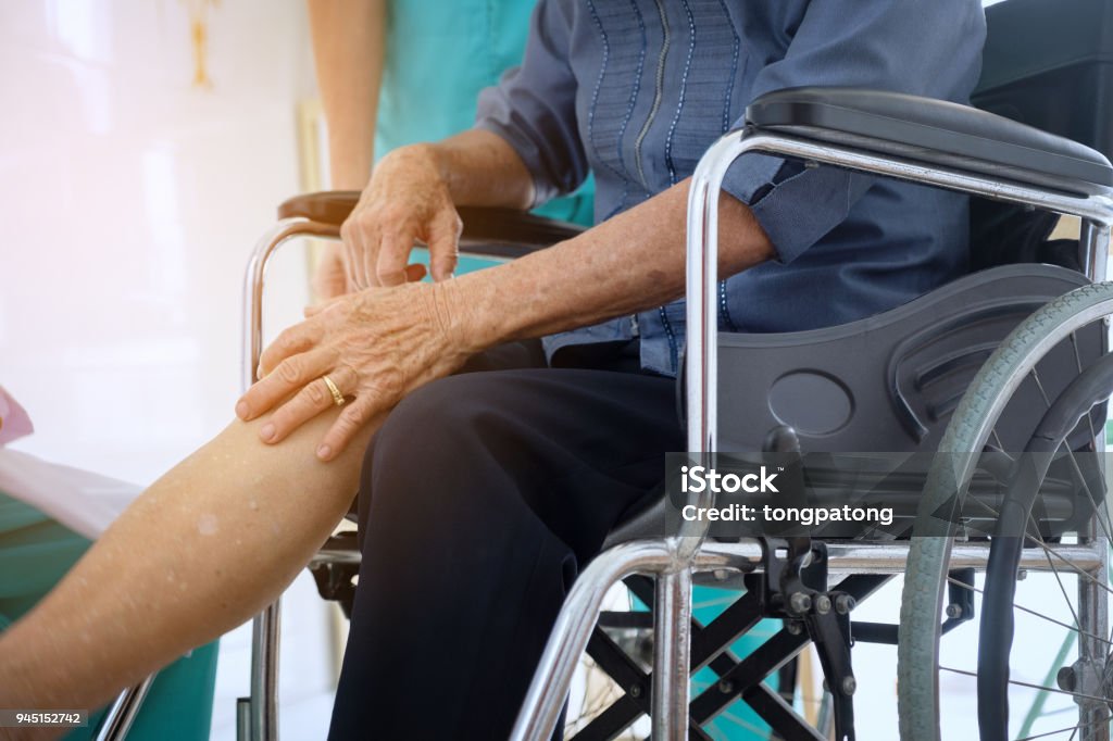 Senior oder ältere Dame Frau Patientin zeigen ihre Narben op Knie Symptome, die gemeinsame sitzen im Rollstuhl Pflege Krankenhaus leidet unter Schmerzen im Knie. - Lizenzfrei Knie Stock-Foto