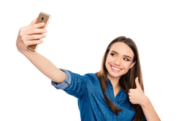 szczęśliwa wesoła młoda kobieta pokazująca kciuk w górę i robiąc selfie na smartfonie - telephone child isolated on white elegance zdjęcia i obrazy z banku zdjęć