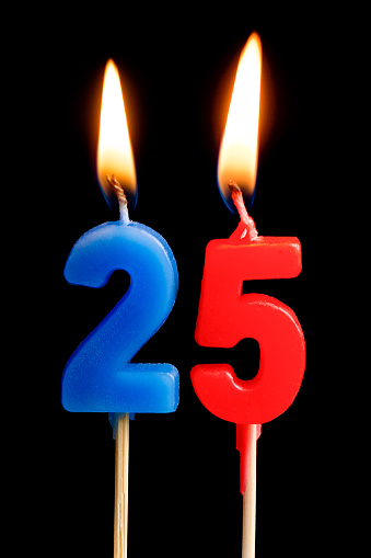 Burning candles in the form of 25 twenty five figures (numbers, dates) for cake isolated on black background. The concept of celebrating a birthday, anniversary, important date, holiday, table setting