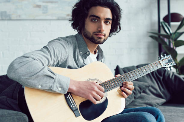 istock handsome guitarist looking at camera at home 945156360
