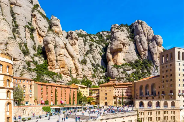 Top view of Santa Maria de Montserrat Abbey in Monistrol de Montserrat (Montserrat Monastery) and big, high rocky mountains  on sunny day, Catalonia, Spain