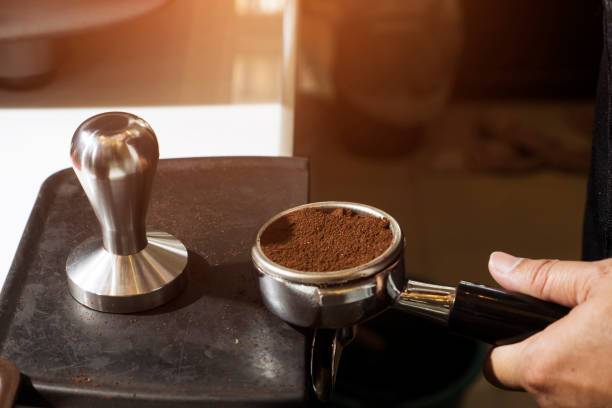 barista ravvicinato premendo il caffè macinato in portafilter manomettendo la produzione di caffè - tampering foto e immagini stock