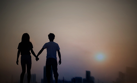 silhouette of a couple standing out of city at dawn or dusk with sky sunset.