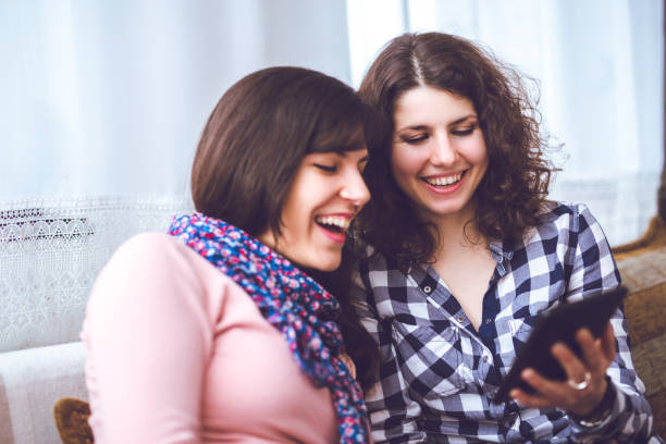 istock Two cheerful woman relaxing indoor and using tablet. 945182456