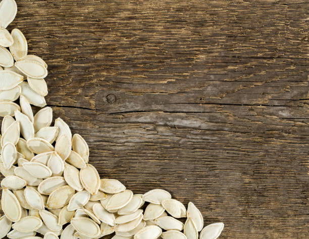 istock Pumpkin seeds on a background of rough wood texture. 945183774